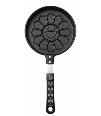Pancake maker featuring Murakami's iconic flower design with a smiling face, black handle, and flowe.
