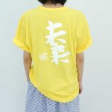 Bright yellow T-shirt featuring bold white Japanese characters by Yoshitomo Nara and Satoshi Ohno.