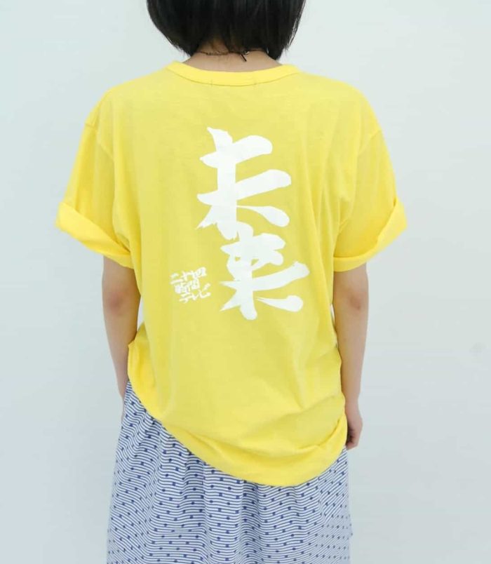 Bright yellow T-shirt featuring bold white Japanese characters by Yoshitomo Nara and Satoshi Ohno.