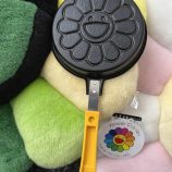 Cute flower-shaped pancake maker with yellow handle, perfect for creating cheerful breakfast treats.