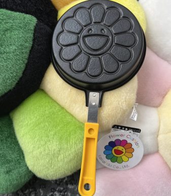Cute flower-shaped pancake maker with yellow handle, perfect for creating cheerful breakfast treats.