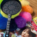 Pancake maker featuring Murakami's flower design with a black handle.
