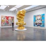Gold sculpture and colorful Murakami artworks at art gallery.