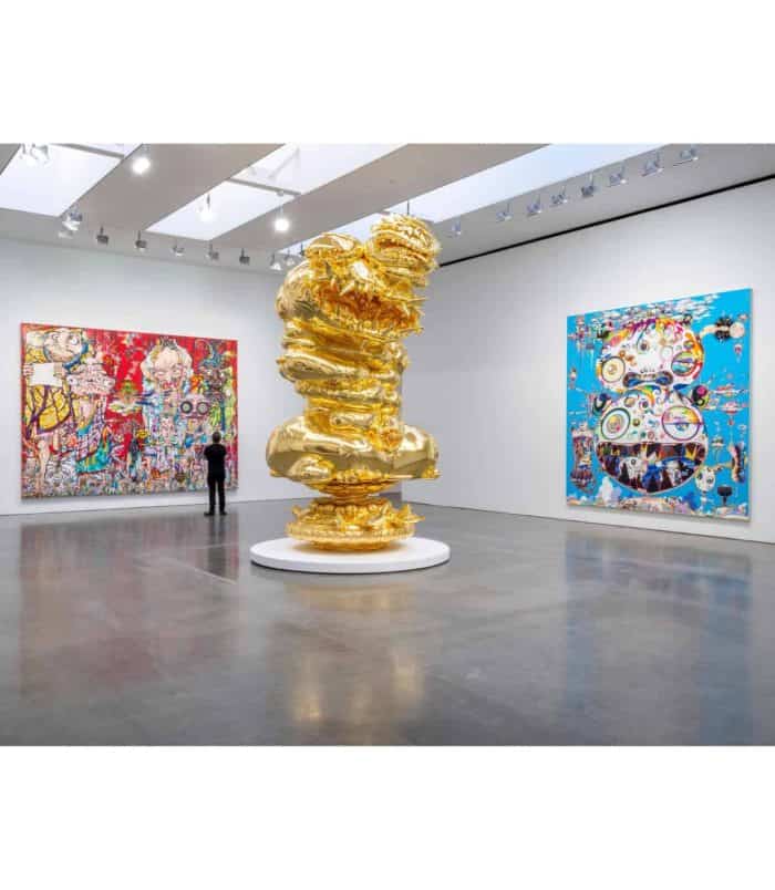 Gold sculpture and colorful Murakami artworks at art gallery.