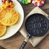 Flower-shaped pancake maker with black handle, inspired by Takashi Murakami's art.