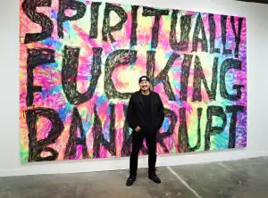Man standing in front of colorful graffiti wall with bold "Spiritually F***ing Banned" message.