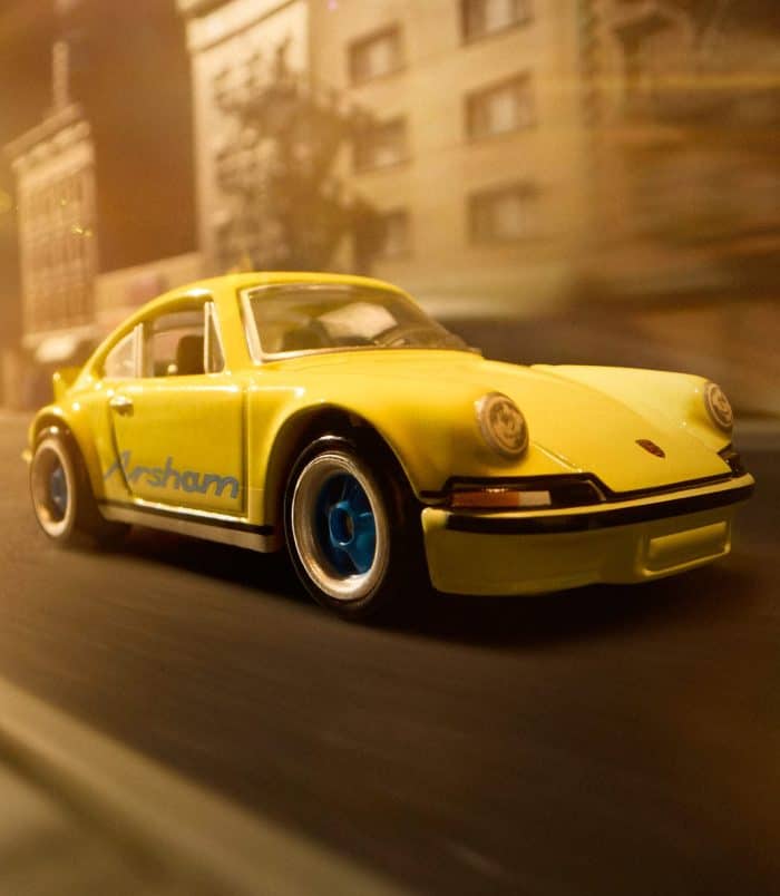 Yellow Porsche toy car on city street at night, blurred background. Yellow Porsche toy car, detailed and vibrant, racing through city streets at night.