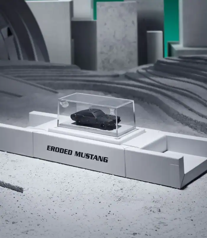 Eroded Mustang Model Display Miniature black Mustang car model in a clear display case on a white platform.