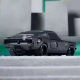 Damaged black vintage toy car with scratches and dents.