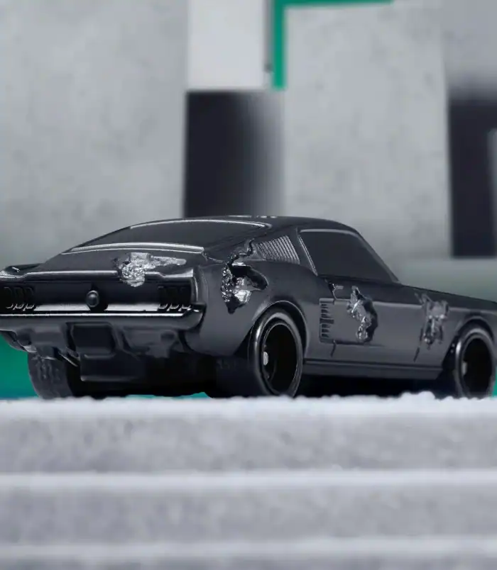 Black vintage toy car with damage, close-up shot. Damaged black vintage toy car with scratches and dents.