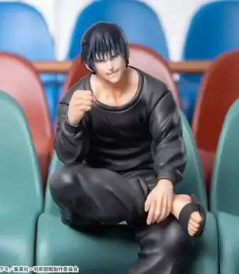Anime figurine of a young man with black hair, sitting on stadium seats, smiling confidently.